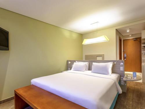 a bedroom with a large bed with white pillows at Mercure Salvador Rio Vermelho in Salvador