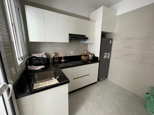 Elle comprend une petite cuisine avec des placards blancs et un réfrigérateur noir. dans l'établissement Charming, Peaceful Apartment, Sea, à Tanger