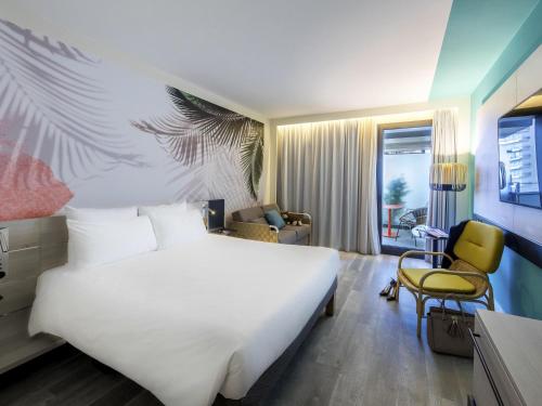 a hotel room with a large white bed and a chair at Novotel Monte-Carlo in Monte Carlo
