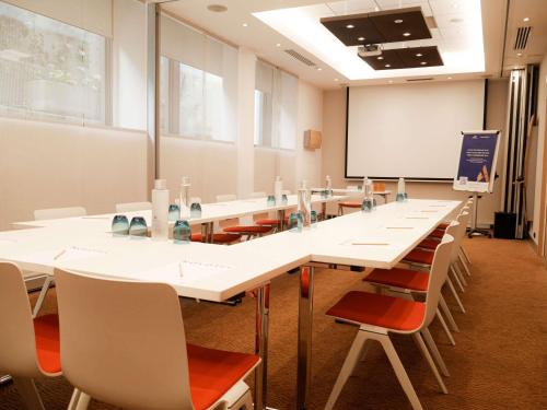 a conference room with white tables and chairs and a whiteboard at Novotel Monte-Carlo in Monte Carlo