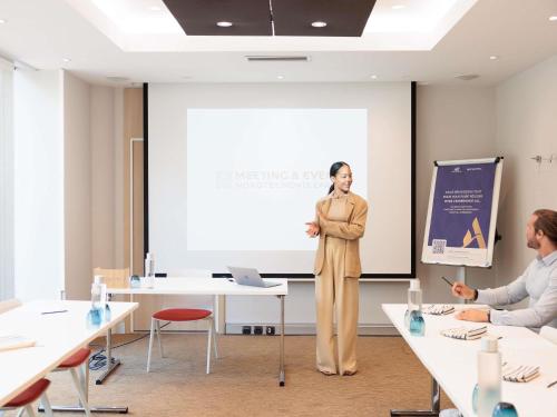 a woman standing in front of a screen in a room at Novotel Monte-Carlo in Monte Carlo