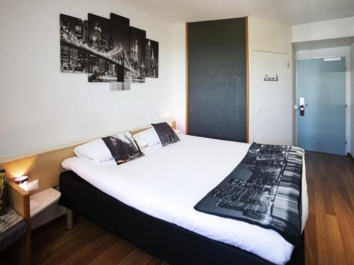 a bedroom with a large bed with white sheets at ibis Fribourg in Fribourg