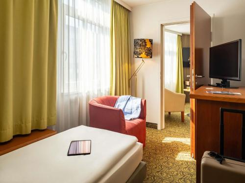 a hotel room with a chair and a television at Hotel Mercure Wien Westbahnhof in Vienna