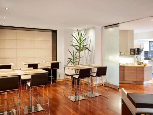 a restaurant with tables and chairs and a kitchen at Mercure Hotel Düsseldorf City Center in Düsseldorf
