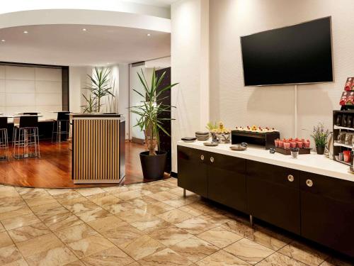 a living room with a television on a wall at Mercure Hotel Düsseldorf City Center in Düsseldorf