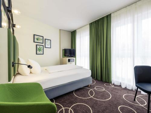 a hotel room with a bed and a green chair at Mercure Hotel Hannover Mitte in Hannover