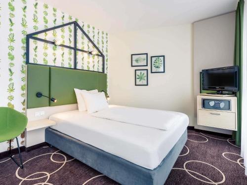 a hotel room with a bed and a tv at Mercure Hotel Hannover Mitte in Hannover