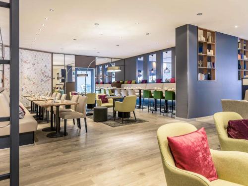 a restaurant with tables and chairs and a bar at Mercure Hotel Hannover Mitte in Hannover