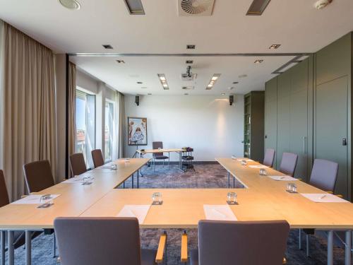a conference room with long tables and chairs at Mercure Hotel Hannover Mitte in Hannover
