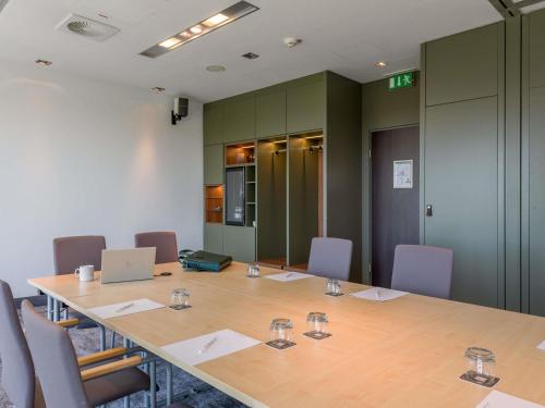 a conference room with a long table with chairs and a laptop at Mercure Hotel Hannover Mitte in Hannover