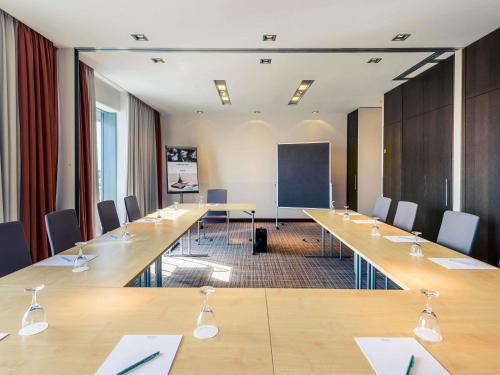 a conference room with long wooden tables and chairs at Mercure Hotel Hannover Mitte in Hannover