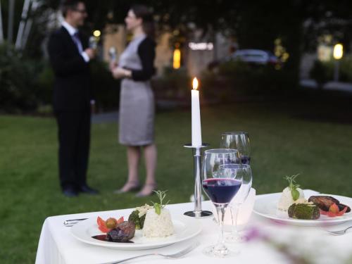 a table with two plates of food and wine glasses at Novotel Hildesheim in Hildesheim