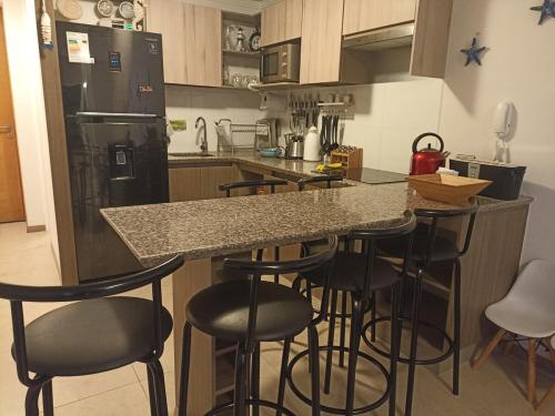a kitchen with a counter and bar stools at Hermoso y acogedor departamento, excelente ubicación! in Coquimbo