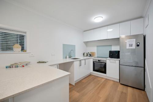 KhandallahにあるCosy Studio Retreat - Wellington Holiday Homeの白いキッチンには白い家電製品が備わり、ウッドフロアです。