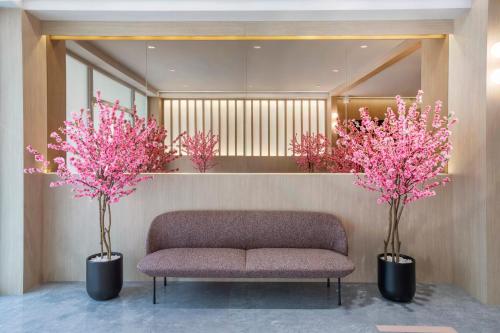 a lobby with a couch and two pink trees at Hotel Sakura by Venue in Singapore