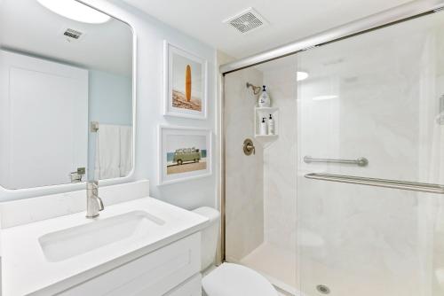 a white bathroom with a sink and a shower at Sandcastles 413 in Cocoa Beach
