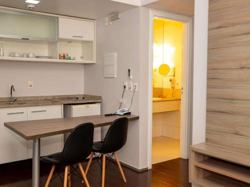 a kitchen with a wooden table and two chairs at Mercure Manaus in Manaus