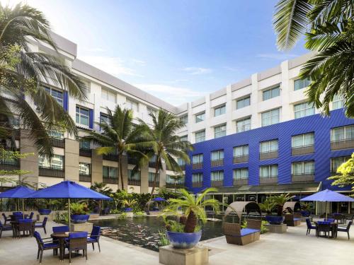 a hotel with tables and umbrellas in a courtyard at Novotel Jakarta Mangga Dua Square in Jakarta