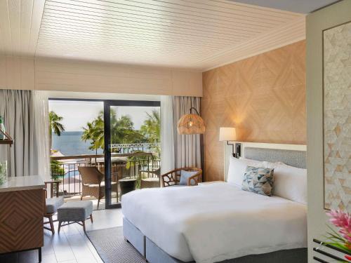 una camera da letto con un letto e un balcone con vista sull'oceano di Sofitel Fiji Resort & Spa a Denarau