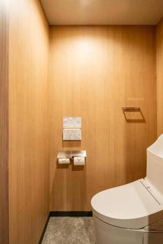 a bathroom with a white toilet and wooden walls at Pyramiden view inn in Banī Ghālib