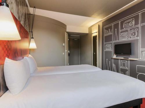 a bedroom with a white bed and a tv at Ibis Albi in Albi