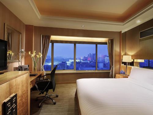 a hotel room with a bed and a desk and a window at Sofitel Xi'an On Renmin Square in Xi'an