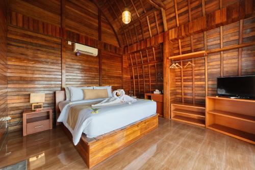 ein Schlafzimmer mit einem Bett und einem Fernseher und Holzwänden in der Unterkunft Sinta Nusa Villa in Nusa Penida