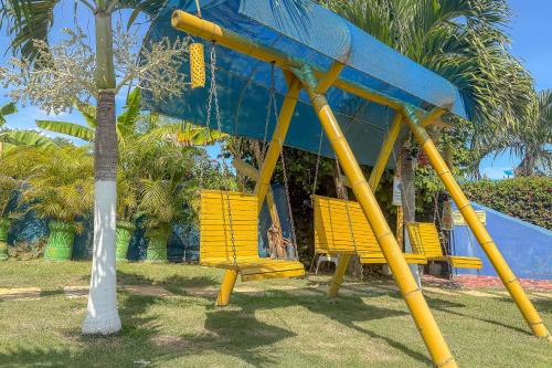 a group of yellow park benches next to a palm tree at La Rivera Playa Palomino in Palomino