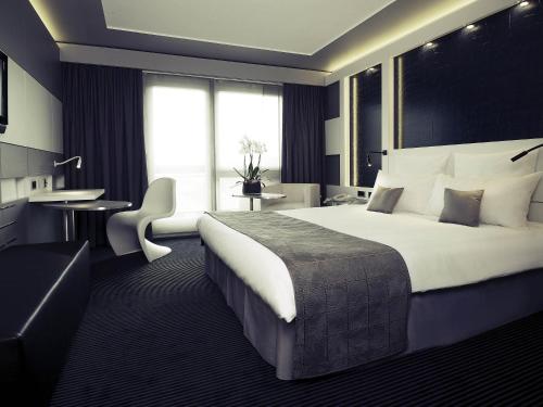 a hotel room with a large bed and a desk at Mercure Biel in Biel