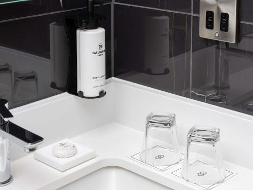 a white counter with two glasses and a bottle on it at Sofitel London Gatwick in Horley