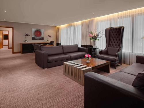 a living room with a couch and a chair and a table at Sofitel London Heathrow in Hillingdon