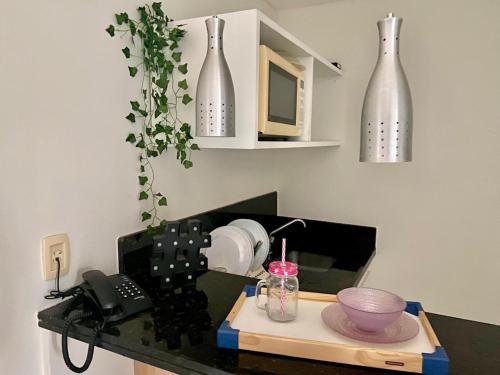 a kitchen with a counter with vases on the wall at Apartamento Aldeia das Águas l Condomínio Village das Águas in Barra do Piraí