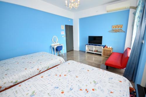 una camera da letto blu con due letti e una sedia rossa di Dreamer 24 B&B a Città di Taitung