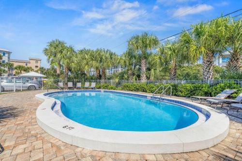 a swimming pool in a yard with palm trees at Blue Tide 6B in Inlet Beach