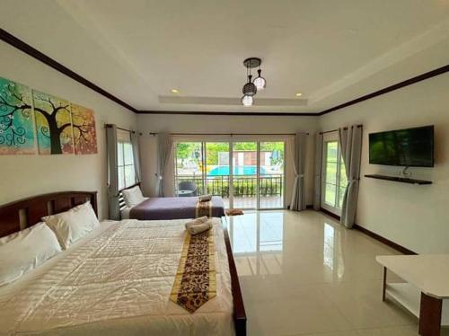 a bedroom with a large bed and a tv at Monmai Resort Huahin in Hua Hin