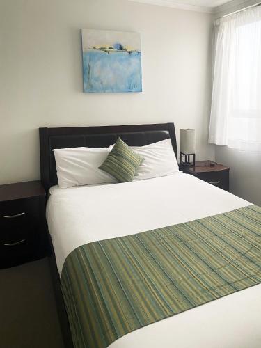 a bedroom with a large bed with a green and white blanket at Curtis Central Apartments Official in Gladstone