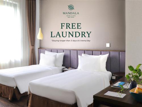 two beds in a hotel room with a free laundry sign on the wall at Mandala Hotel & Spa Bac Ninh in Bắc Ninh