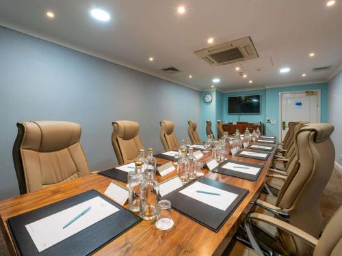 a conference room with a long wooden table and chairs at Mercure Manchester Norton Grange Hotel & Spa in Rochdale