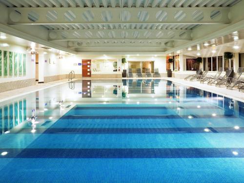 a large pool with blue water in a building at Mercure Manchester Norton Grange Hotel & Spa in Rochdale