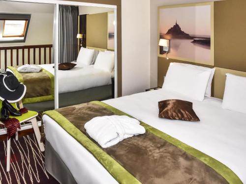 a hotel room with two beds and a mirror at Mercure Granville Le Grand Large in Granville