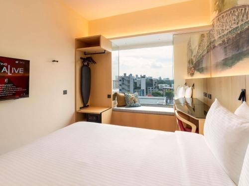 a bedroom with a white bed and a large window at Ibis Singapore on Bencoolen - Newly Renovated in Singapore
