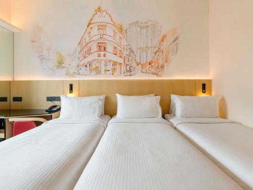 two beds in a room with a painting on the wall at Ibis Singapore on Bencoolen - Newly Renovated in Singapore