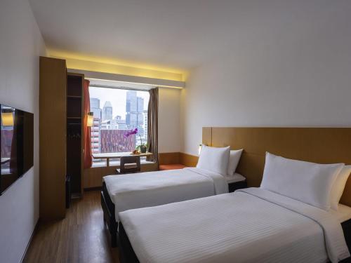 a hotel room with two beds and a window at Ibis Singapore on Bencoolen - Newly Renovated in Singapore
