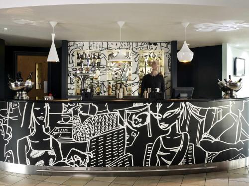 a man standing behind a counter with a wall covered in graffiti at ibis Swansea in Swansea