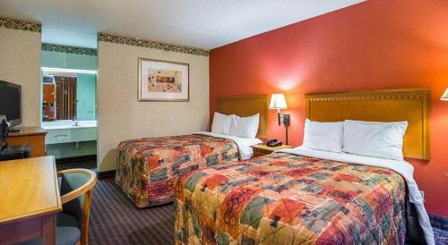 two beds in a hotel room with red walls at Rodeway Inn & Suites in Tupelo