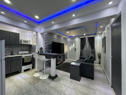 a living room with a table and a kitchen with blue lights at Modern Apartment in Levittown near Beach & Boulevard in Levittown