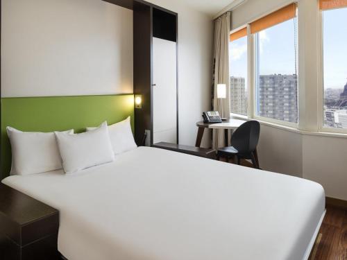 a hotel room with a large bed and a desk at Aparthotel Adagio Paris Centre Tour Eiffel in Paris