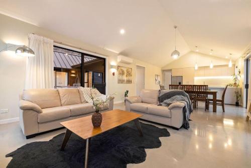 a living room with two couches and a table at Modern Luxe Jacks Point Living in Queenstown Airport