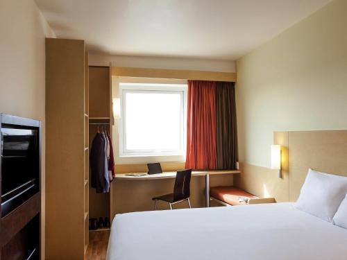 a hotel room with a bed and a desk and a window at Ibis Juarez Consulado in Ciudad Juárez