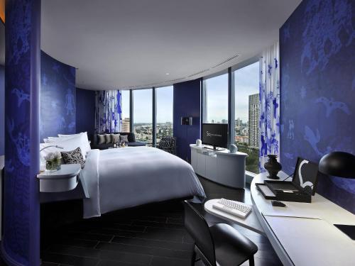 a hotel room with a bed and a desk with a computer at SO/ Bangkok in Bangkok